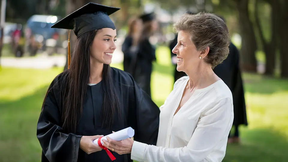Grandmother congratulating granddaughter at graduation ceremony — legacy giving and family celebration concept