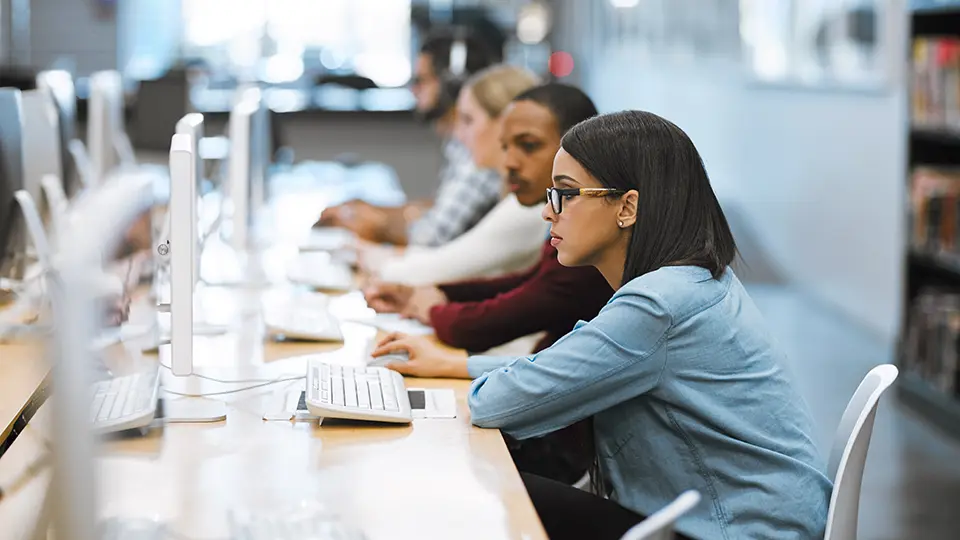 College students studying on desktop computers in a university computer lab