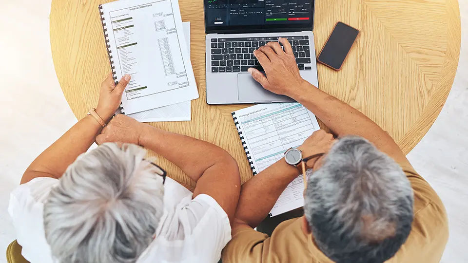 Senior couple reviewing investment and charitable giving plans on laptop